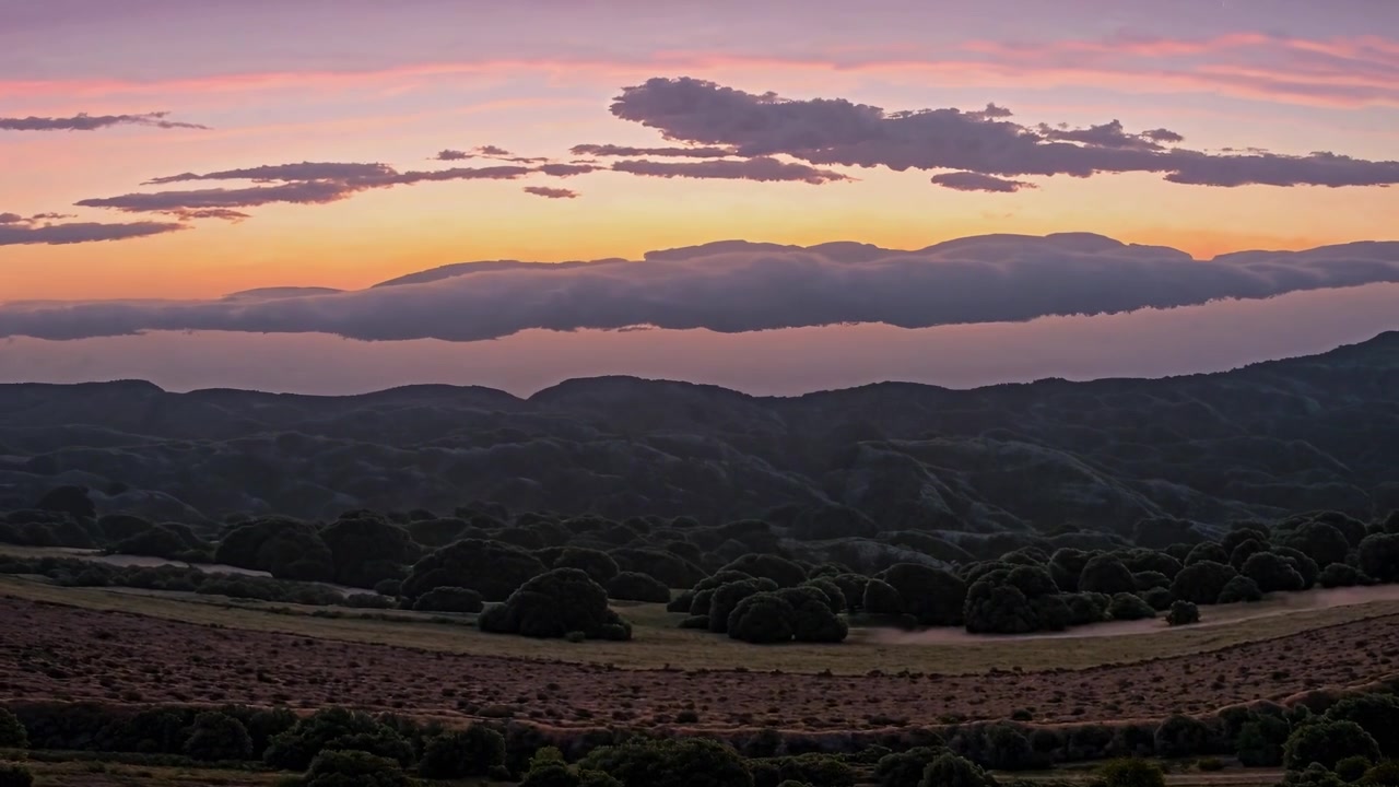 Time-lapse di un tramonto su colline ondulate e nuvole