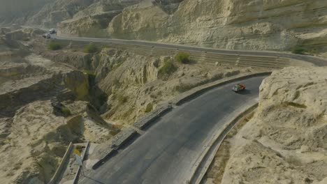 aerial shot capturing a truck navigating the dramatic curves of the makran coastal highway in balochistan, set against rugged mountainous terrain