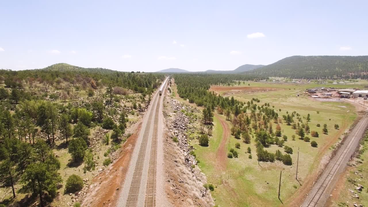 imágenes aéreas de drones del tren de pasajeros silver amtrack que se dirige al oeste a california a lo largo de las vías en williams arizona