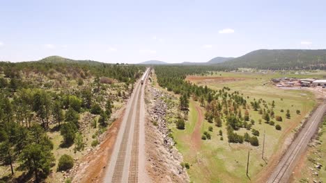 aerial drone footage of silver amtrack passenger train heading west to california along the tracks at williams arizona