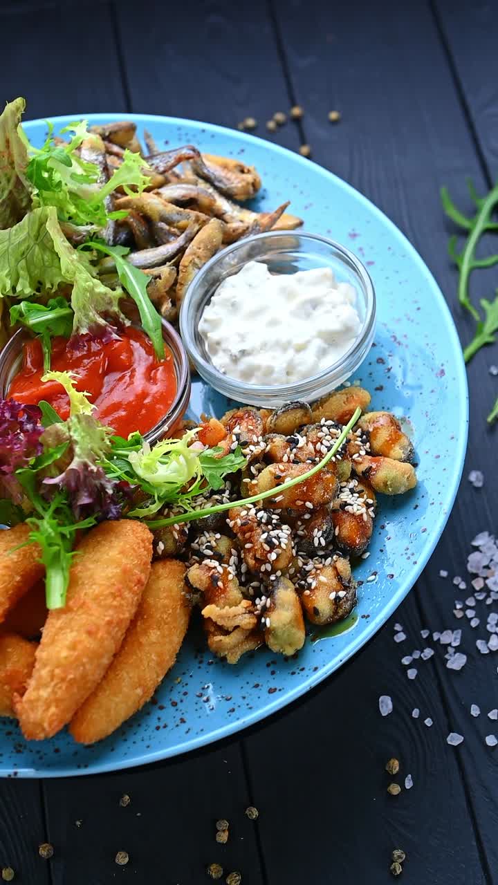 Delizioso vassoio di cibo con vari piatti e salse per pranzo o cena. Un vassoio colorato con pesce, samosa, salse e insalata è pronto da mangiare.