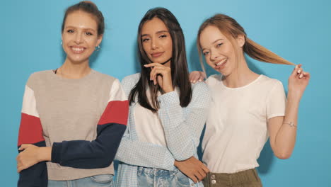 three women posing in front of a blue background