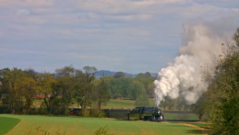 Vista-De-Un-Tren-De-Pasajeros-De-Vapor-Antiguo-Que-Viaja-A-Través-De-árboles-Y-Tierras-De-Cultivo-En-Un-Día-De-Otoño