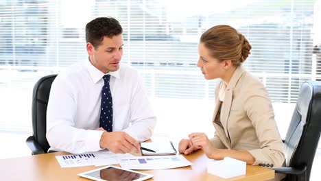 business team looking at documents together at desk and shaking hands