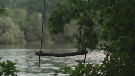 shot of a homemade swing blowing in the wind beside a lake