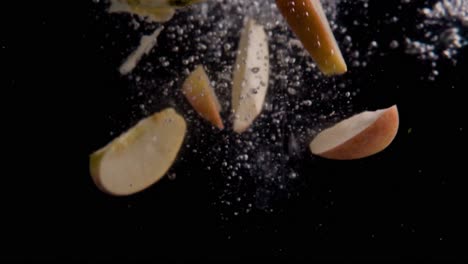 rebanadas de manzana cayendo en cámara superlenta de agua, fondo negro, muchas burbujas de aire, 4k240fps