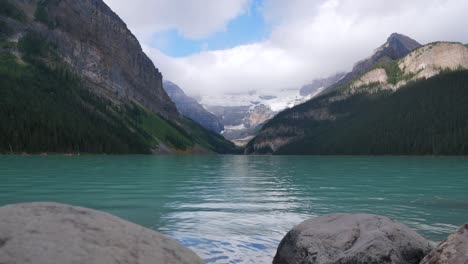 timelapse landscape view of lake louise-one of the most famous lake in banff national park, alberta,canada-in summer daytime after raining with cloud in the sky and people canoeing in lake