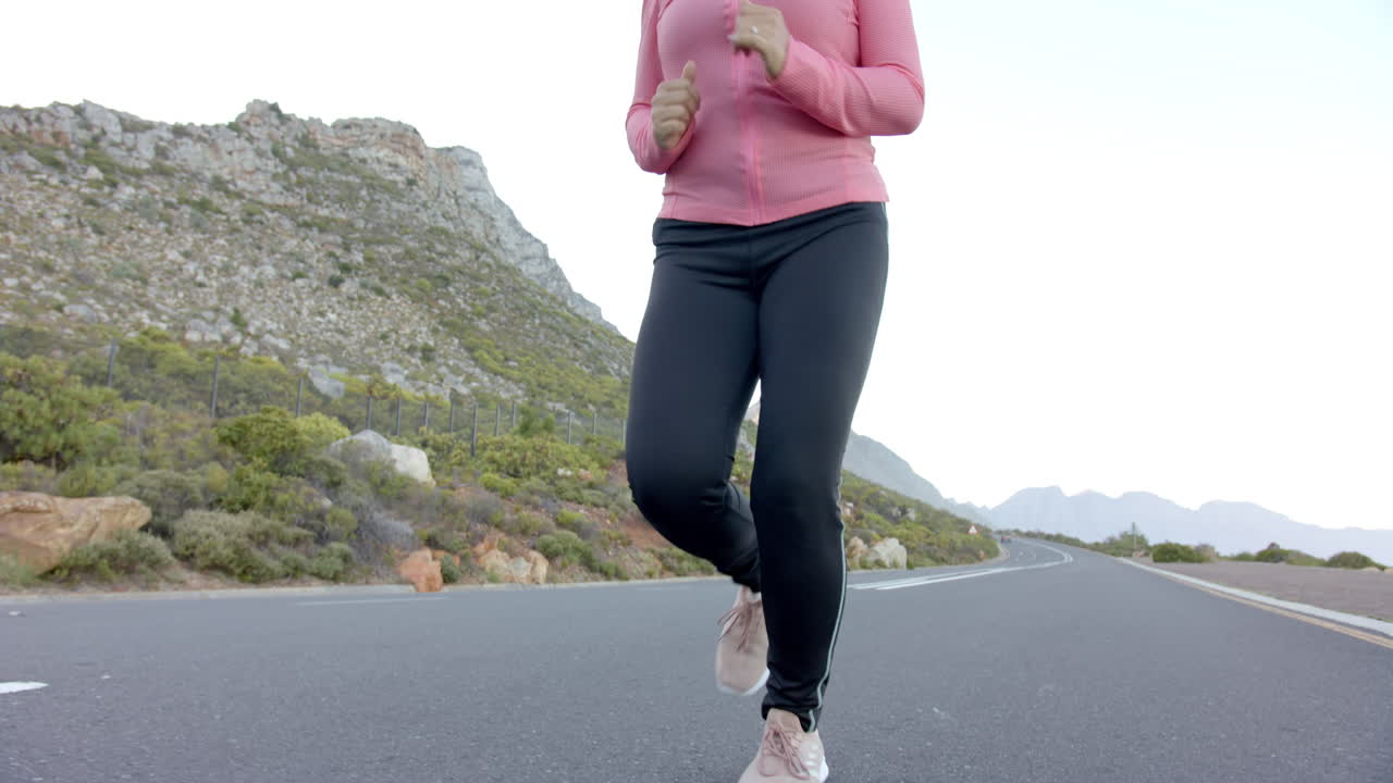 Jogging on mountain road, woman in pink jacket enjoying outdoor exercise