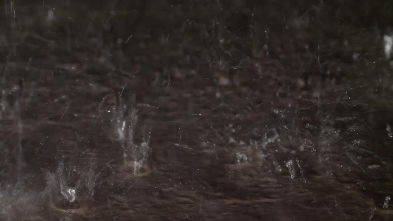 Rain drops bouncing off of concrete sidewalk during a heavy rain shower