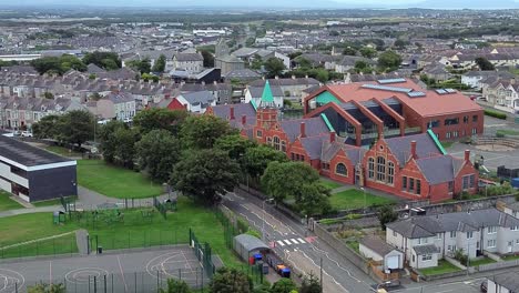 modern and old style red brick welsh school with green spire on holyhead island north wales aerial
