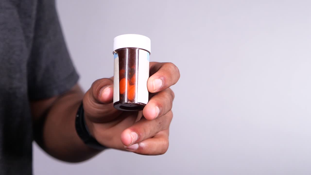 persona que sostiene una botella de pastillas