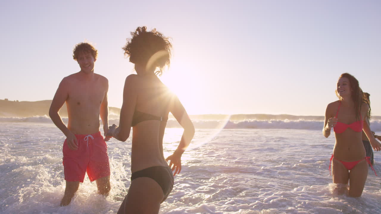 해가 지면 바다 에서 수영 하는 다양한 친구 들 의 그룹