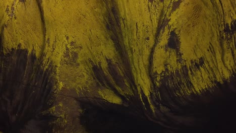 vista aérea sobre texturas naturales y patrones del terreno montañoso oscuro de las tierras altas islandesas, con hierba verde brillante