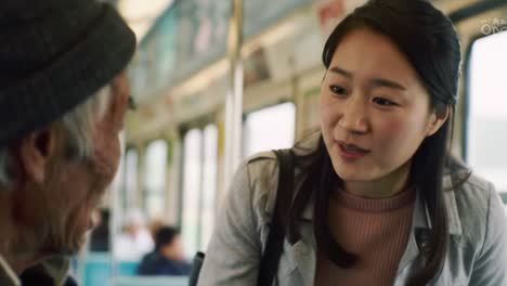 a woman shares a heartfelt discussion with an elderly man while riding a bus. the warm interaction highlights the connection between generations in a bustling city.