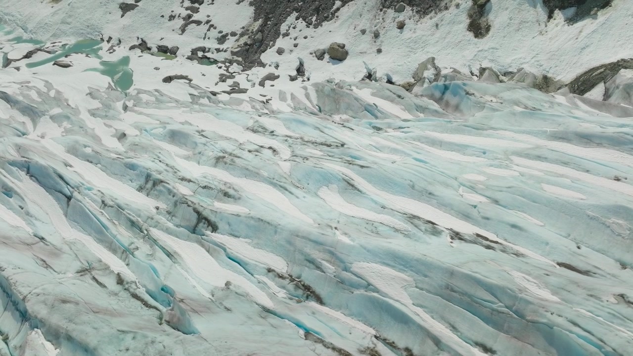 Espectacular vista aérea de las grietas de un glaciar, que exhibe texturas, tonos de hielo azul profundo y dramáticos patrones naturales formados a lo largo de los siglos.