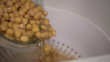 pouring soaked chick peas and water into white colander or strainer