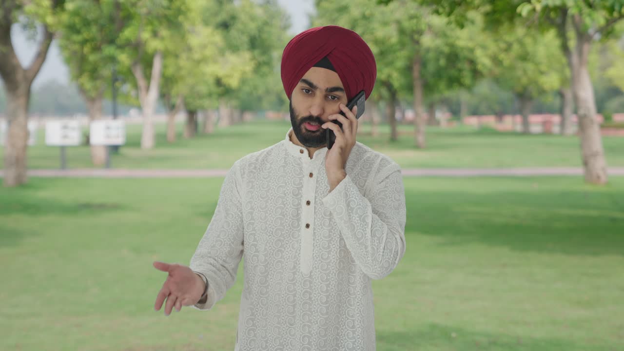 Angry Sikh Indian man shouting on someone on phone in park