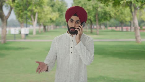 hombre indio sikh enojado gritando a alguien por teléfono en el parque