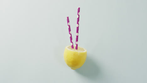 video of lemon cut in half with straws lying on white background