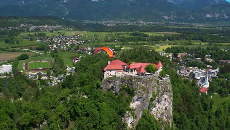 Vista-Aérea-Del-Parapente-Que-Se-Eleva-Sobre-Las-Aguas-Del-Lago-Bled-En-Eslovenia