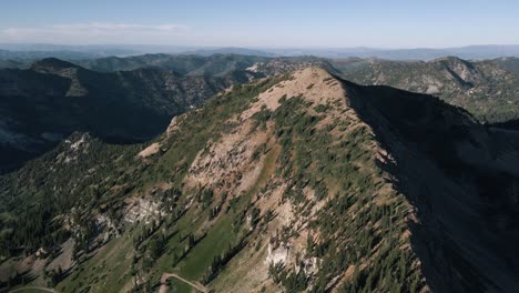 ascending aerial view to the top of a mountain ridge in utah near snowbird ski resort on a sunny summer day