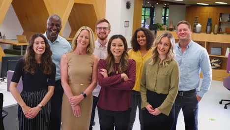 portrait of smiling multi-cultural business team standing in modern open plan office