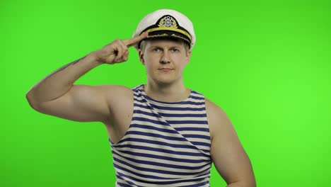 young sailor man salutes with hand to camera. seaman guy in sailor's vest