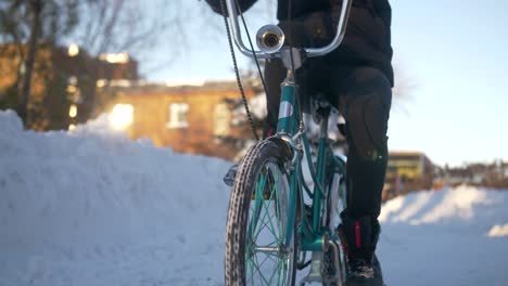 close up of a person riding a retro vintage style bicycle through the snow