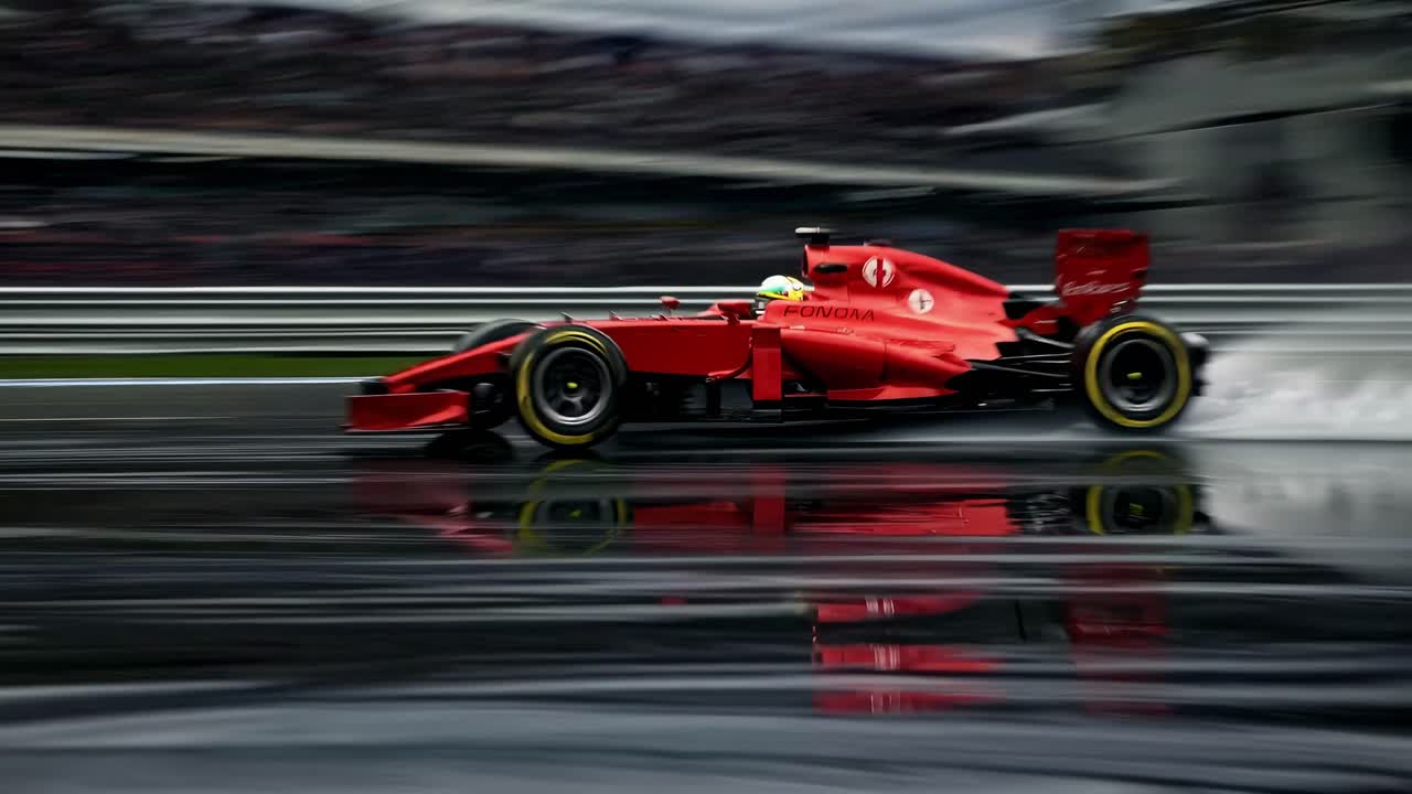 Dynamisk sidebilde av en rød Formel 1-bil som kjører på en våt bane, tatt med panoreringsteknikk