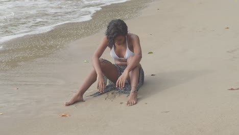 sexy girl in a bikini sitting in the sand before standing up