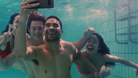 cool friends taking photo underwater using smartphone in swimming pool having fun swim submerged in clear water