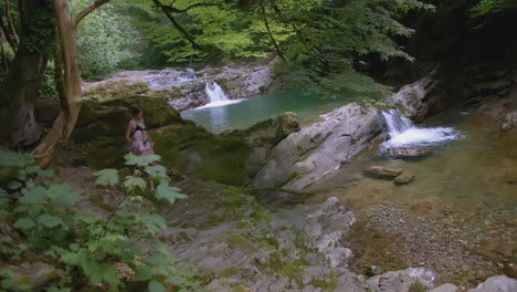 woman hiking near a waterfall in a forest