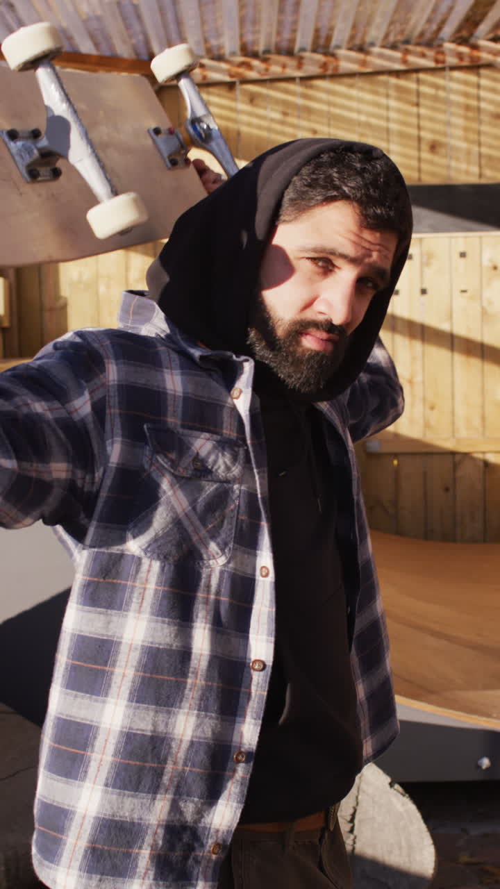 video vertical de un skateboarder masculino de oriente medio en un parque de skate