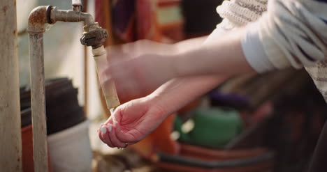 Female-Gardener-Washing-Hands-In-Tap-In-Garden