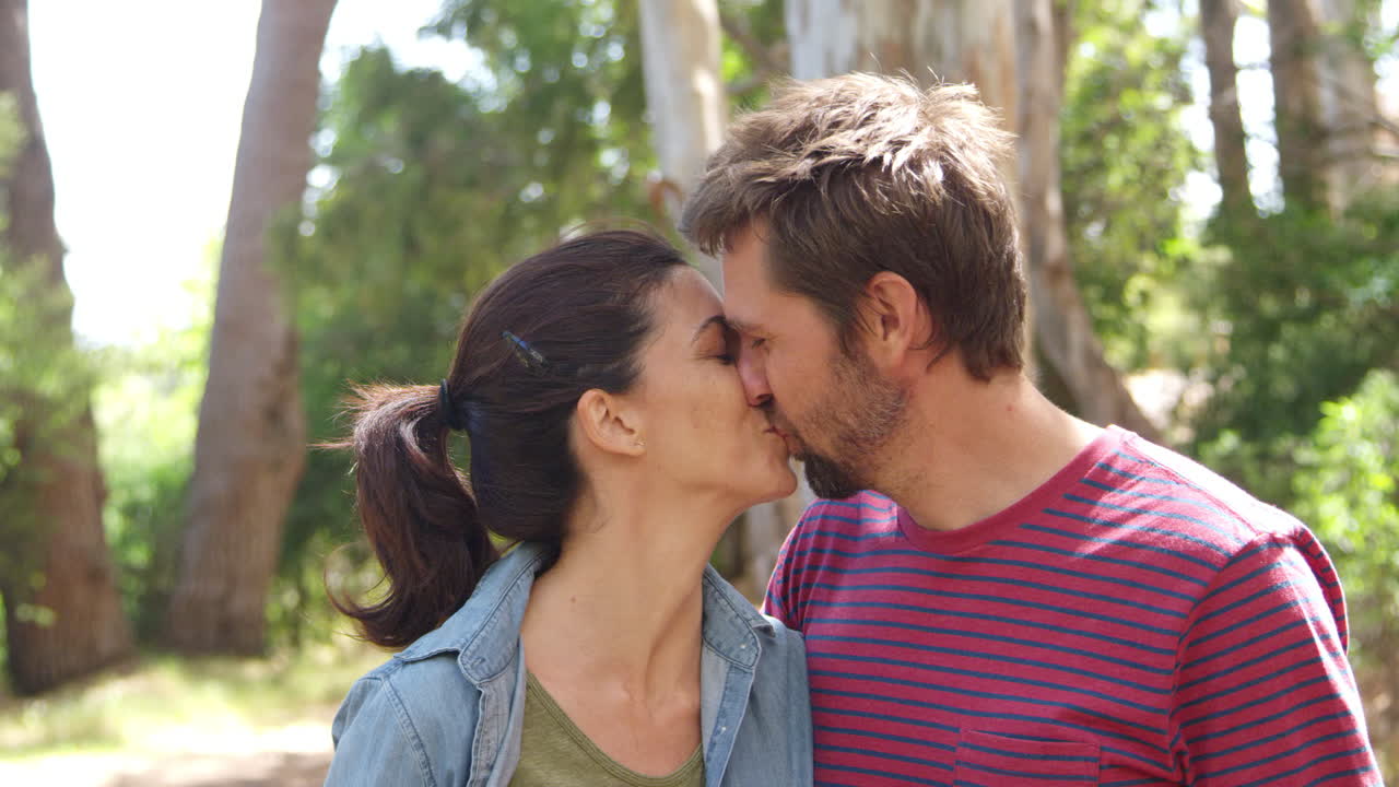 Ritratto di coppia romantica che si bacia mentre cammina nel bosco