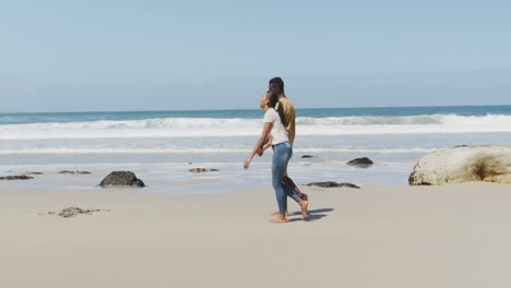 african american couple holdings hands and walking at the beach