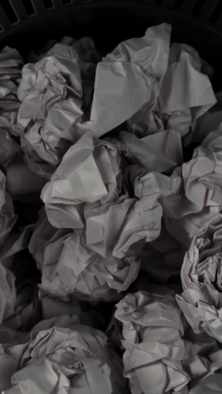 Crumpled White Paper Filling a Black Trash Can