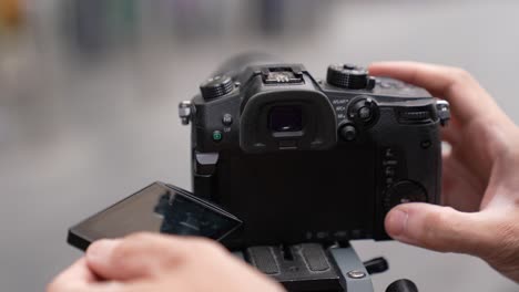 close up of a caucasian man's hands, adjusting the settings for his camera with the touch screen