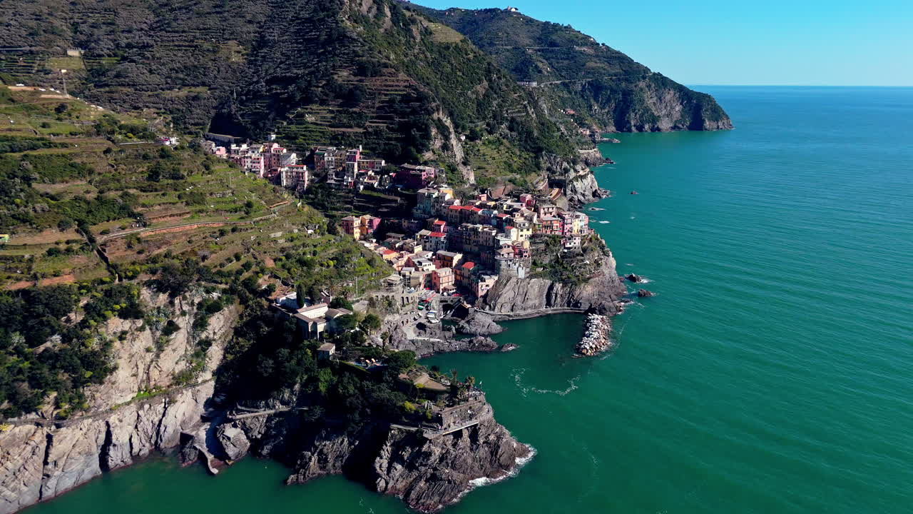 Colorful coastal view of Manarola, Cinque Terre, Italy with steep hills and blue sky
