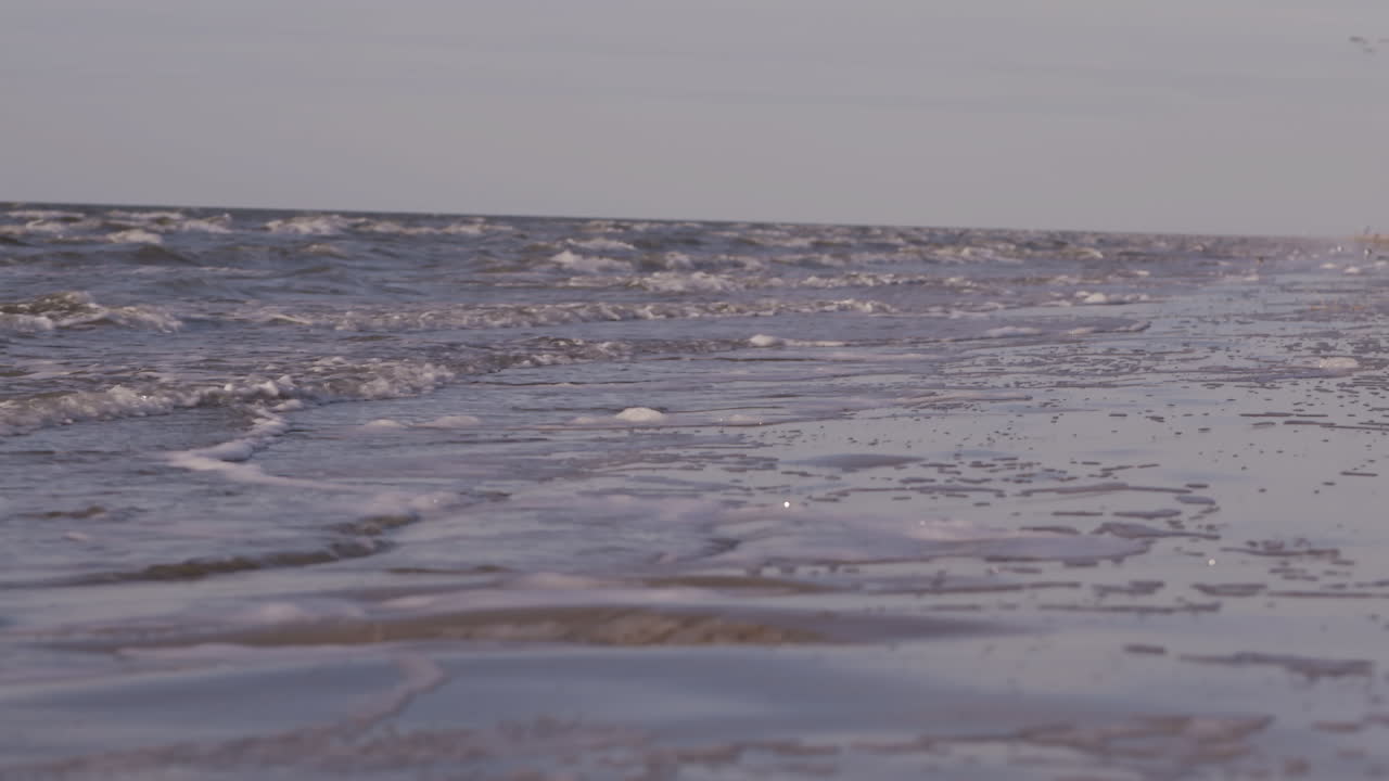 일몰 동안 해변에서 돌진하는 바다 파도