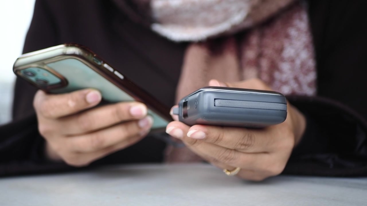 Persona che tiene uno smartphone e un power bank portatile