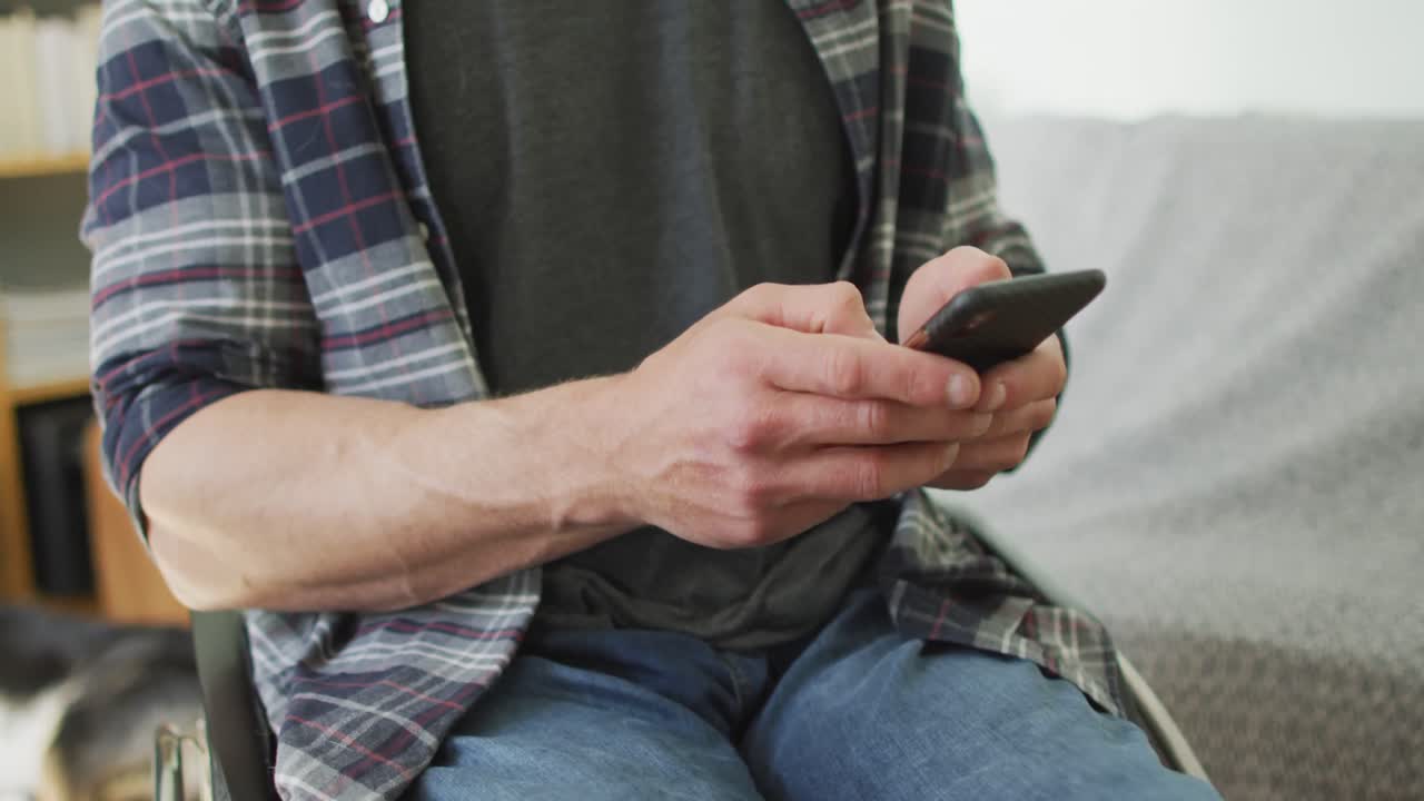 거실에서 스마트폰을 사용하는  ⁇ 체어에 앉은 행복한 백인 장애인