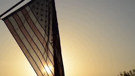 united states flag blowing in a light breeze with the sunset behind it