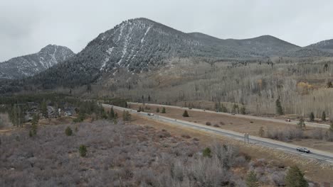 Aerial-dolly-shot-pushing-toward-Interstate-70-with-snow-covered-green-mountains-in-the-distance