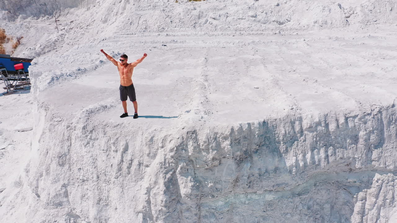 Healthy man running on white canyon. Shirtless athlete training happily on beautiful natural background in summertime. Aerial view.