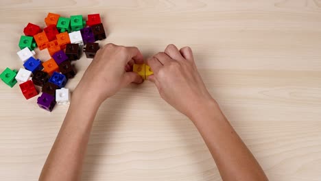 manos montando cubos amarillos en una mesa de madera