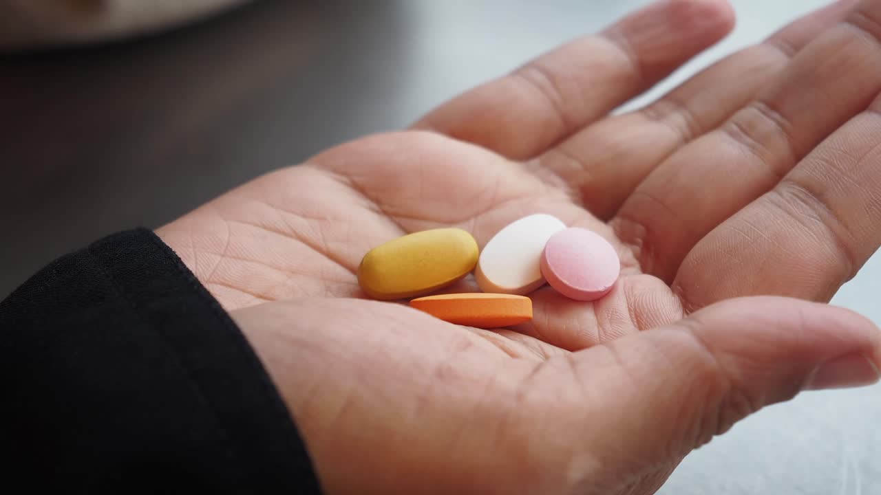 Hand holding various colored pills