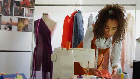 Front-view-of-African-American-female-fashion-designer-looking-at-cloth-samples-in-workshop-4k