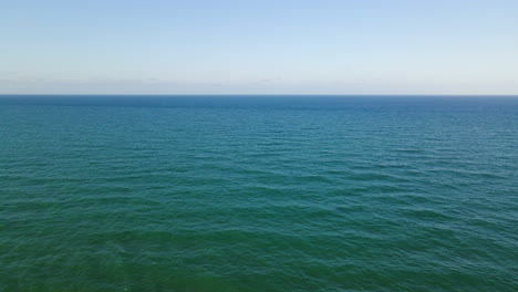 aerial view of the horizon line of the mediterranean sea on a clear day with waves coming in