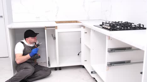 male repairman assembles furniture using an electronic screwdriver male repairman assembles furniture using an electronic screwdriver professional installation of furniture